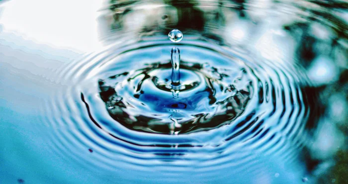 Water droplet creating ripples in clear pond Water droplet creating ripples in clear pond