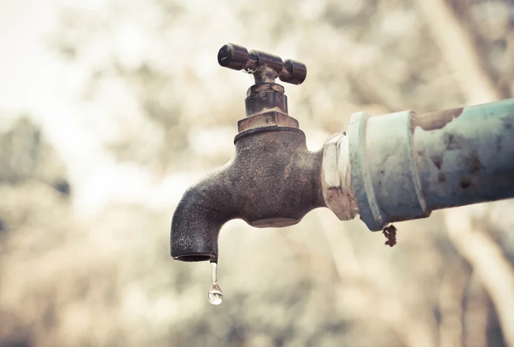 Rusty outdoor faucet with dripping water droplet