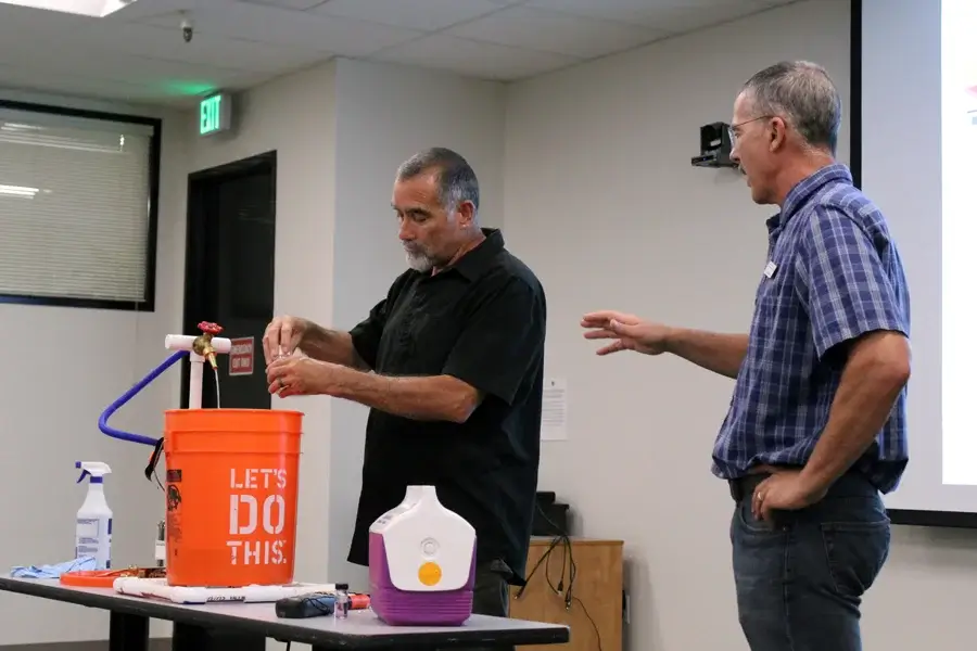 Two men demonstrating water filtration system setup.