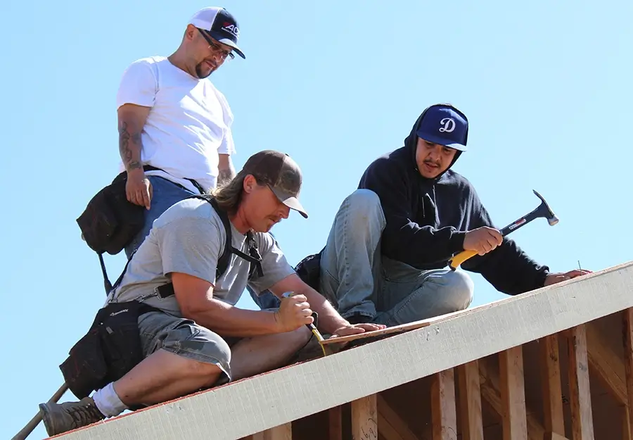 Construction workers fixing roof on sunny day
